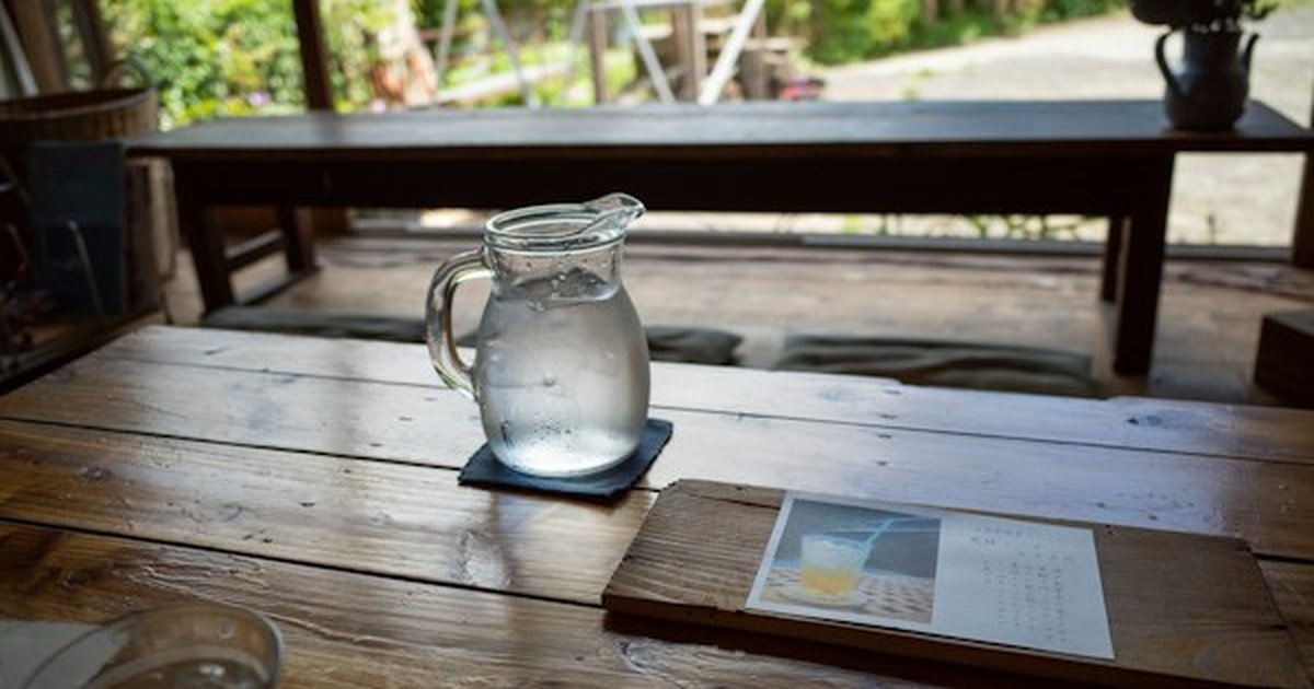 Clear glass water carafe and drinking tumbler on natural wood table avoiding plastic containers