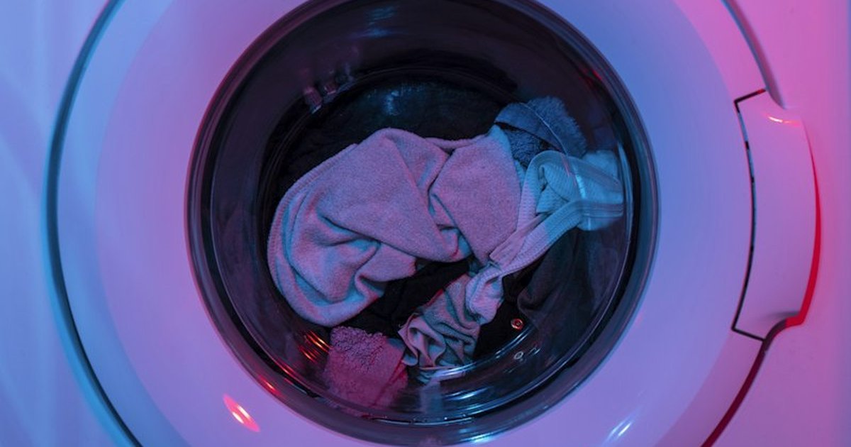 Front-loading washing machine drum containing synthetic laundry fabrics that shed microfibers