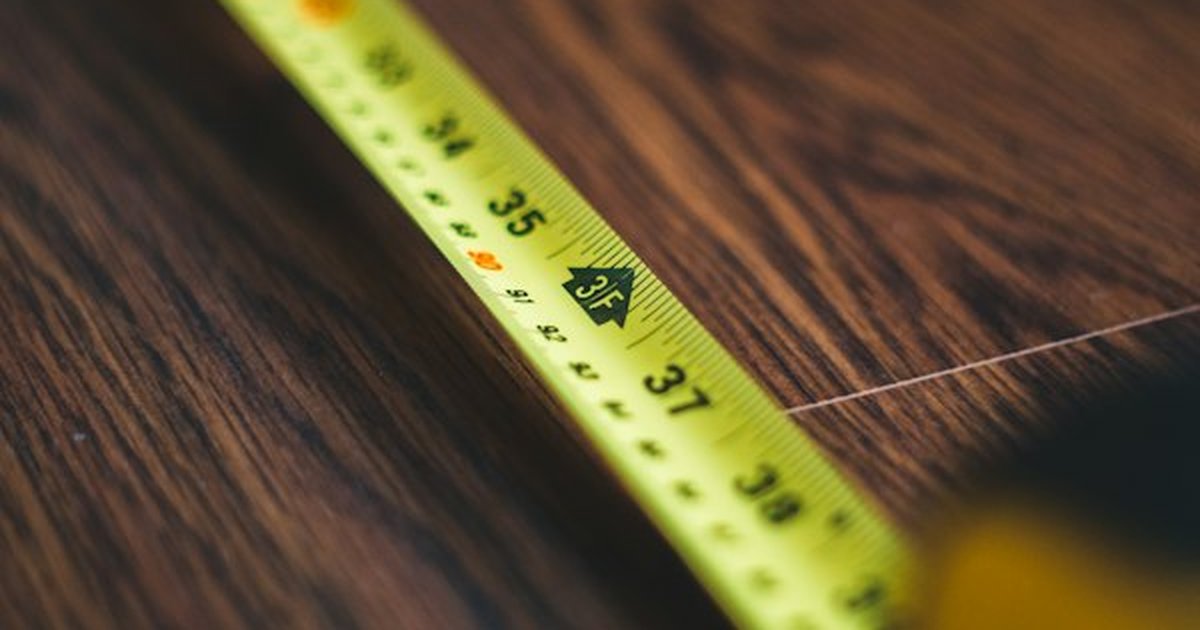 Precision measuring tape placed on dark wood plank in carpentry workshop