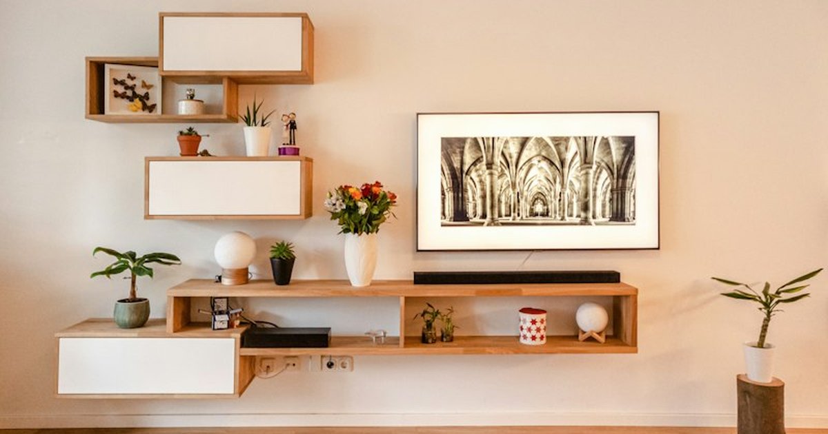 Contemporary modular floating wooden wall shelving styled with potted greenery and books around wall television