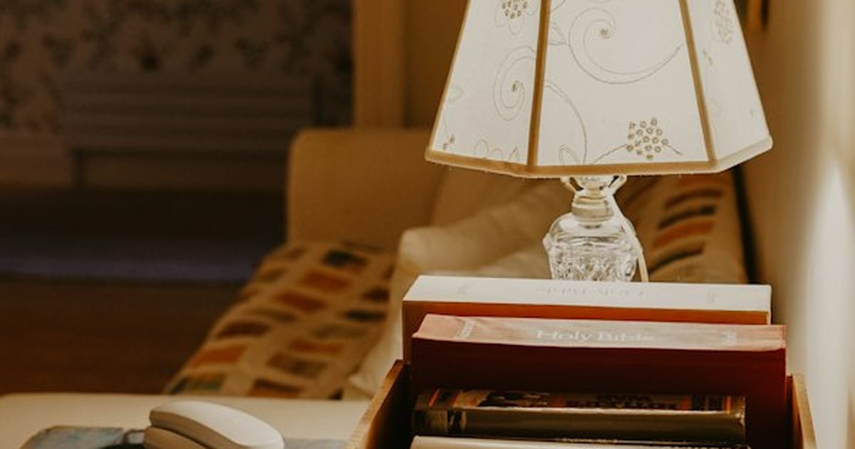 Warm bedside table reading lamp illuminating book collection at night without overhead glare