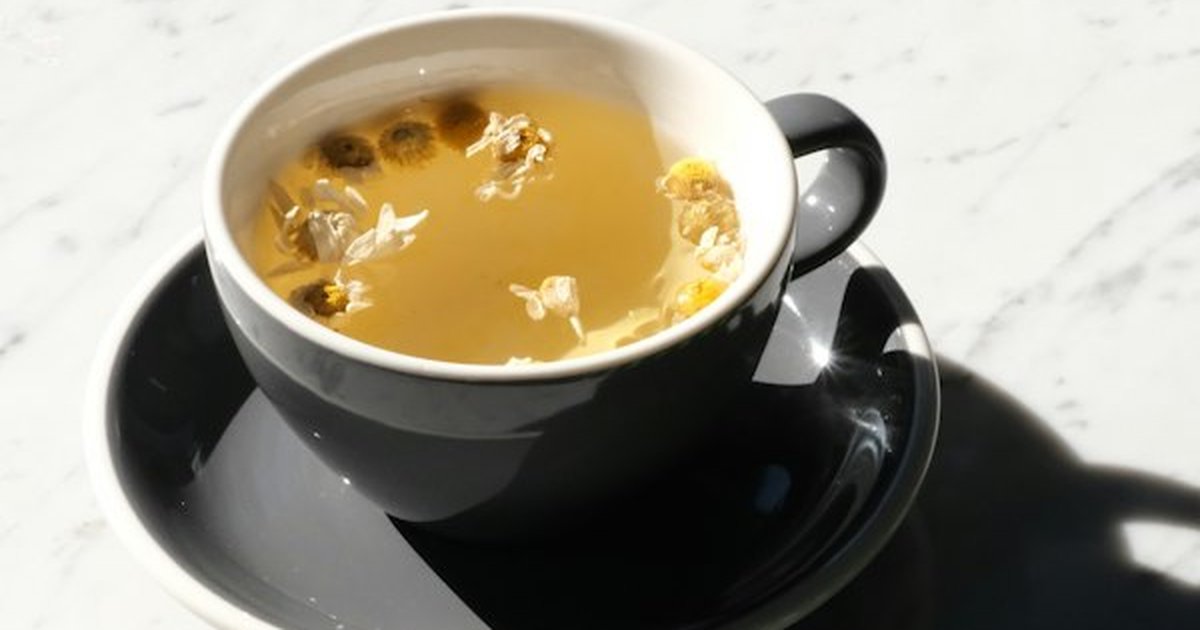 Steaming cup of chamomile herbal tea in ceramic mug on nightstand for restorative evening relaxation