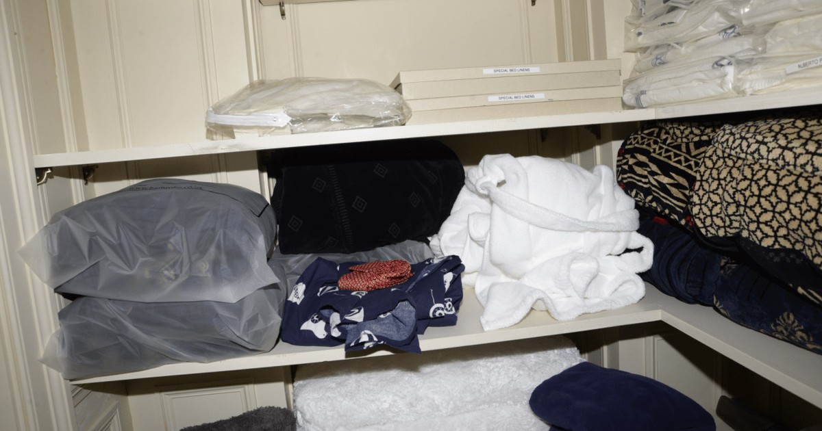 Closet shelves with labeled linen storage boxes and breathable garment containers