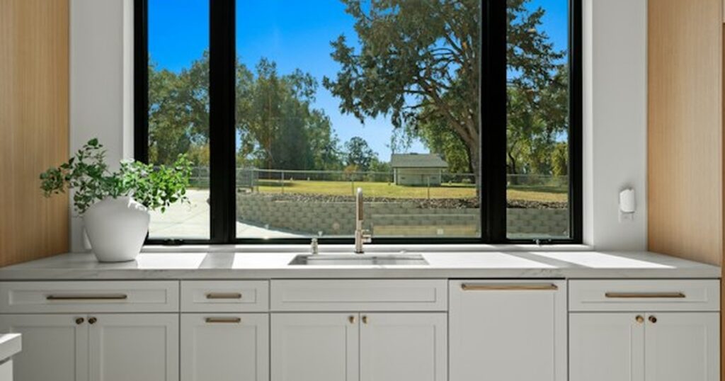 Under-Sink Vanity and Cabinet Organization: Waterproof Liners, Tiered Racks, and Plumbing Clearance Modern kitchen sink counter showing lower cabinet storage space and plumbing fixtures