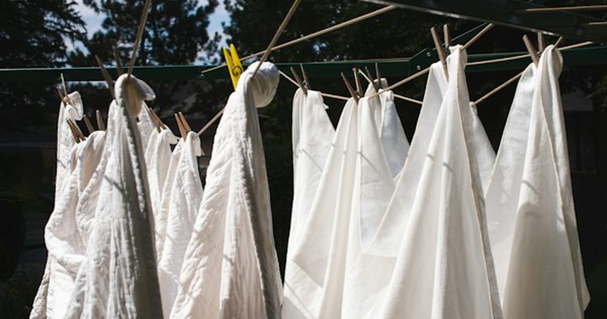 White cotton and linen sheets drying in fresh outdoor sunlight and gentle breeze